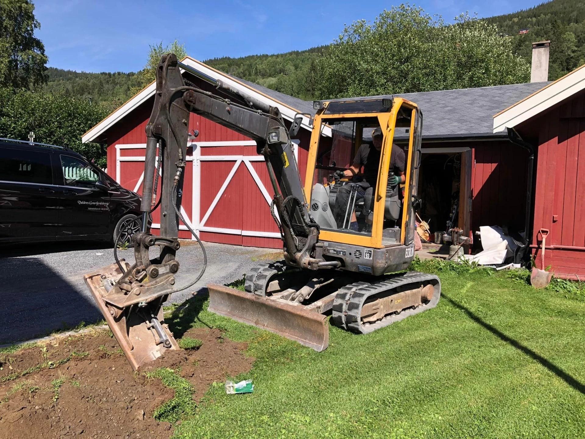 A mini digger at work in the garden of a red house