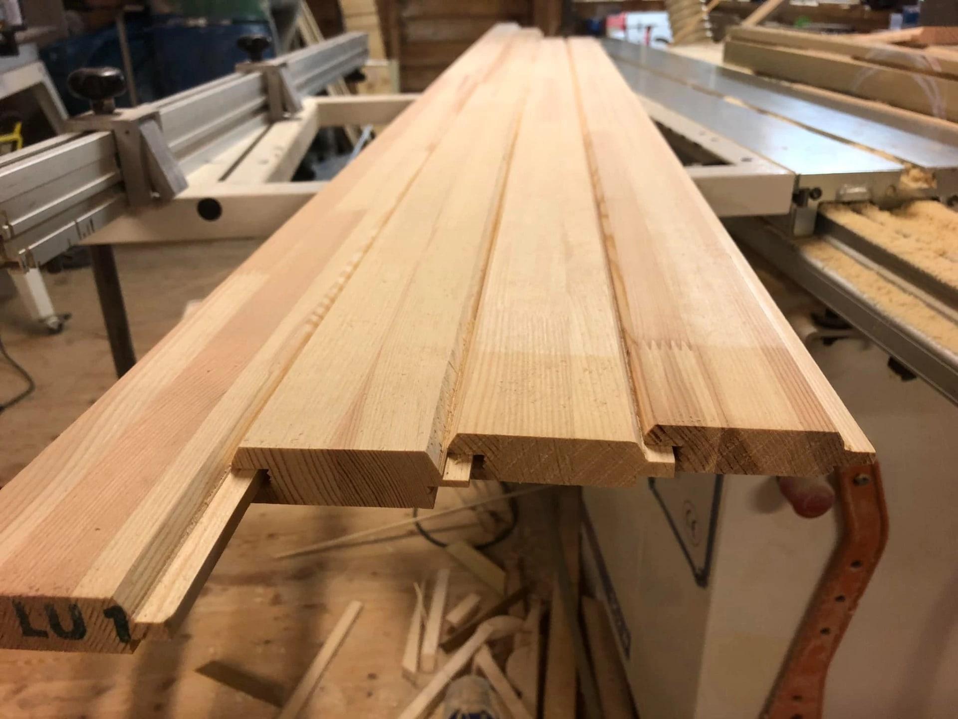 Freshly milled wooden panels with a tongue-and-groove profile, on the machine